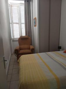 a bedroom with a bed and a chair and a window at Nid douillet in Vals-les-Bains