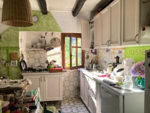 - une cuisine avec des placards blancs et des murs verts dans l'établissement B&B La Scellana, à Tiglieto