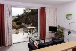 uma sala de estar com um sofá, uma televisão e uma varanda em Moinho Da Asneira - Duna Parque Group em Vila Nova de Milfontes