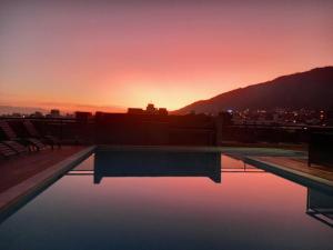 una piscina en la azotea de un edificio con puesta de sol en MIRALEJOS 6 CENTRO en Villa Carlos Paz