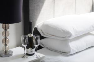 a bed with a bottle of wine and two glasses on a table at Cape Cornwall Club in St. Just