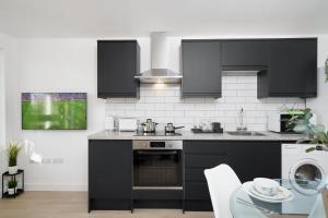 uma cozinha com armários pretos e uma mesa de vidro em Stunning Duplex near Canary Wharf & O2 & City Views em Londres
