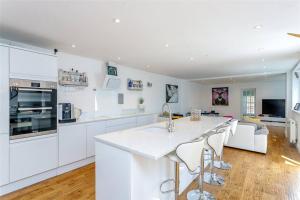 una cocina con armarios blancos y una isla de cocina con taburetes en Northampton Modern Oasis - Spacious & Stylish en Northampton