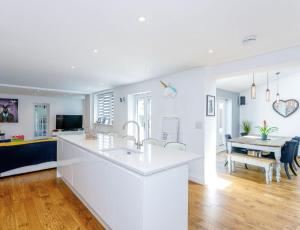 a white kitchen with a sink and a dining room at Northampton Modern Oasis - Spacious & Stylish in Northampton