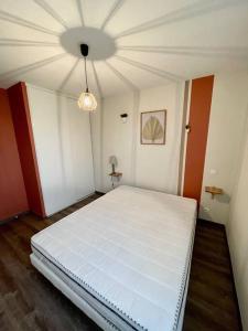 uma grande cama branca num quarto com tecto em La nature aux portes de Toulouse em Pinsaguel