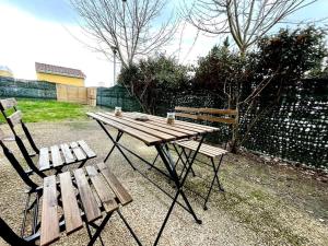 a wooden picnic table and two chairs in a yard at La nature aux portes de Toulouse in Pinsaguel