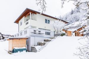 une maison blanche avec de la neige au sol dans l'établissement Haus Raich - Pitztal Card im Sommer inklusive, à Arzl im Pitztal