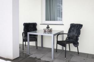 a white table with two black chairs and a table with a glass bowl at Haus Raich - Pitztal Card im Sommer inklusive in Arzl im Pitztal