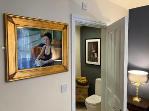 a painting of a woman is hanging on a wall in a bathroom at THE PROMENADE SUITE - 2 min walk to the lovely beach front promernade of llandudno in Llandudno