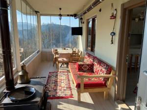 einen Balkon mit einem Tisch und Stühlen sowie einem großen Fenster in der Unterkunft Doğa ile baş başa kalabileceğiniz, sakin kırevi in Rize