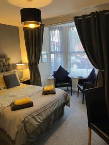 a bedroom with a bed and chairs and a window at THE PROMENADE SUITE - 2 min walk to the lovely beach front promernade of llandudno in Llandudno