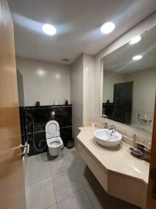 a bathroom with a toilet and a sink and a mirror at Nice cozy studio in Damac Tower Amman 1104 in Amman