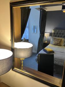 a mirror reflecting a bedroom with a bed and a tub at THE PROMENADE SUITE - 2 min walk to the lovely beach front promernade of llandudno in Llandudno