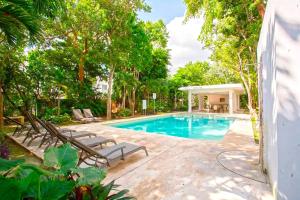 una piscina con tumbonas y una casa en La Casa del Arbol -4bed 3 bath, en Puerto Morelos