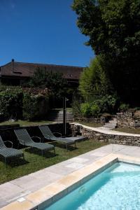 a swimming pool with two chairs and a table at Les Jardins de la Contie in Lunan