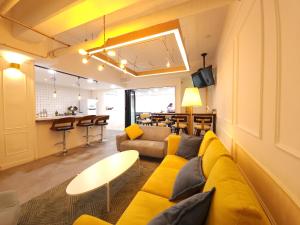 a living room with a yellow couch and a bar at OYO Hostel Myeongdong 5 in Seoul