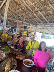 Un groupe de personnes assises à une table avec de la nourriture dans l'établissement Casa da Zélia Hospedagem, à Barreirinhas