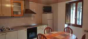 La cuisine est équipée d'une table, d'un évier et d'un réfrigérateur. dans l'établissement Centro Torla 4pax Apartamento, à Torla