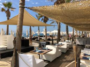 ein Restaurant am Strand mit weißen Stühlen und Sonnenschirmen in der Unterkunft Luxury 3 Bedroom Apartment 300m from the Beach in Fuengirola