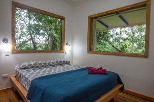 a bedroom with a bed with a blue blanket and two windows at Blue Maverick in Playa Cocles 4x4 neccesary in Cocles