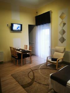 a living room with a table and chairs and a television at Baross-hat apartmanház in Szolnok