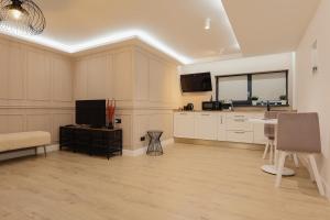 a large kitchen with white cabinets and a television at Aparthotel Nest Inn Meteor in Cluj-Napoca