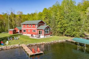 a large red house on the water with a dock at Spacious Lakeside Family Home on Big Bearskin Lake in Hazelhurst