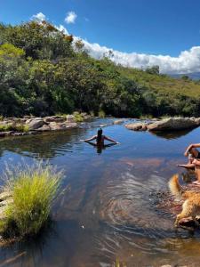a person swimming in a river with a surfboard at Chalés Paradise - Casal in Serra do Cipo +15 photos