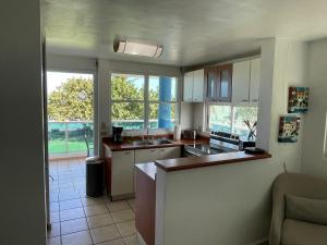 a kitchen with white cabinets and a large window at Costa Mar Beach Front Apartment Whith Pool in Loiza