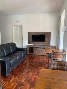 a living room with a leather couch and a flat screen tv at Casa do Alferes in Ouro Preto