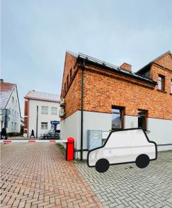 a white car parked in front of a brick building at 1880 Apartment with Private Parking in Marijampolė