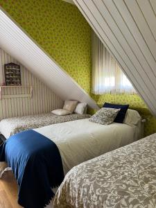 1 dormitorio con 2 camas en una habitación con papel pintado verde en Casa Santiago, en Argoños