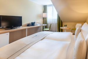 a hotel room with a bed and a flat screen tv at Select Hotel Erlangen in Erlangen