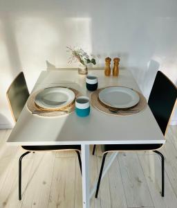 una mesa blanca con 2 platos y 2 sillas en Forest House, Tiidu, en Nässuma