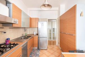 La cuisine est équipée d'armoires en bois et d'un réfrigérateur en acier inoxydable. dans l'établissement 7GF HOME, à Rome