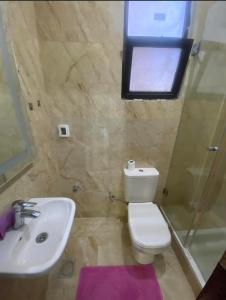 a bathroom with a toilet and a sink and a window at Ground Floor Studio With Garden in Sheikh Zayed