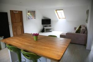 a living room with a wooden table with green chairs at The Paddocks in Pilsdon