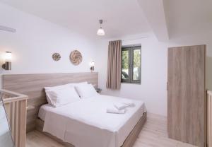 a bedroom with a bed with white sheets and a window at Matala Prime Villas in Matala