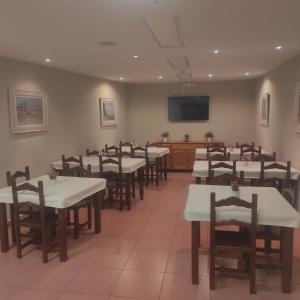 a dining room with tables and chairs and a flat screen tv at Hospedería Hotel Don Quijote in Miguelturra