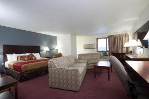 a hotel room with a bed and a couch at Travelodge by Wyndham Merrill in Merrill
