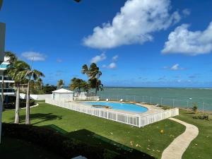 a swimming pool with the ocean in the background at Costa Mar Beach Front Apartment Whith Pool in Loiza