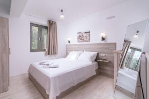 a white bedroom with a large bed and a mirror at Matala Prime Villas in Matala