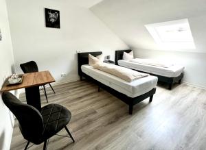 two beds in a room with a table and a chair at Landhotel Laarmann in Lennestadt