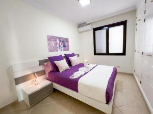 een slaapkamer met een bed met paarse lakens en een raam bij Casa Sol y Mar Azul un'oasi a due passi dal mare in Playa Blanca