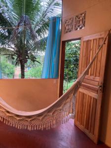 a hammock in a room with a palm tree at Casa Vila Camboinha in Itacaré