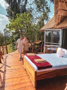 Ein Mann und eine Frau, die auf einer Holzterrasse mit einem Bett spazieren in der Unterkunft Foresight Eco Lodge & Safari in Karatu