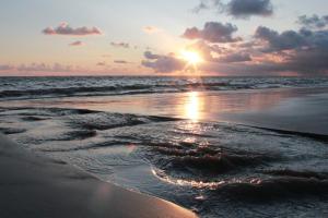 einen Sonnenuntergang am Strand mit dem Meer in der Unterkunft Villa WellenRausch - Adults Only in Travemünde