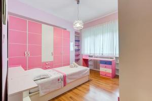 Habitación de color rosa con cama y escritorio. en Exclusive Apartment in Eur Lake en Roma