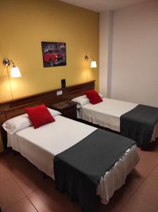 a hotel room with two beds and a red car on the wall at Hospedería Hotel Don Quijote in Miguelturra