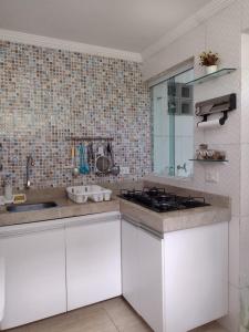 a kitchen with white cabinets and a stove in it at Flat Beach Selma in Porto De Galinhas